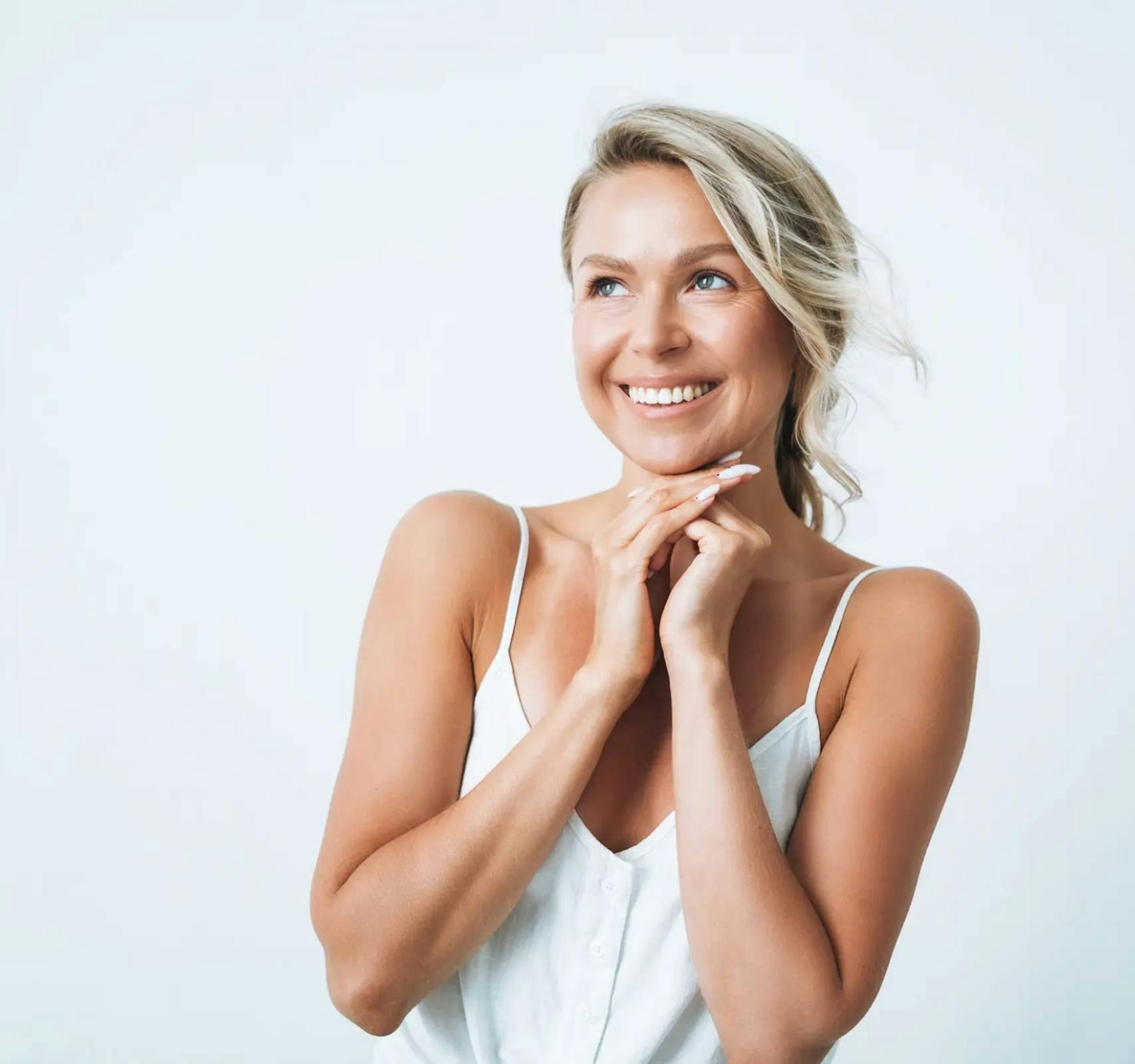 woman smiling with hands clasped under chin