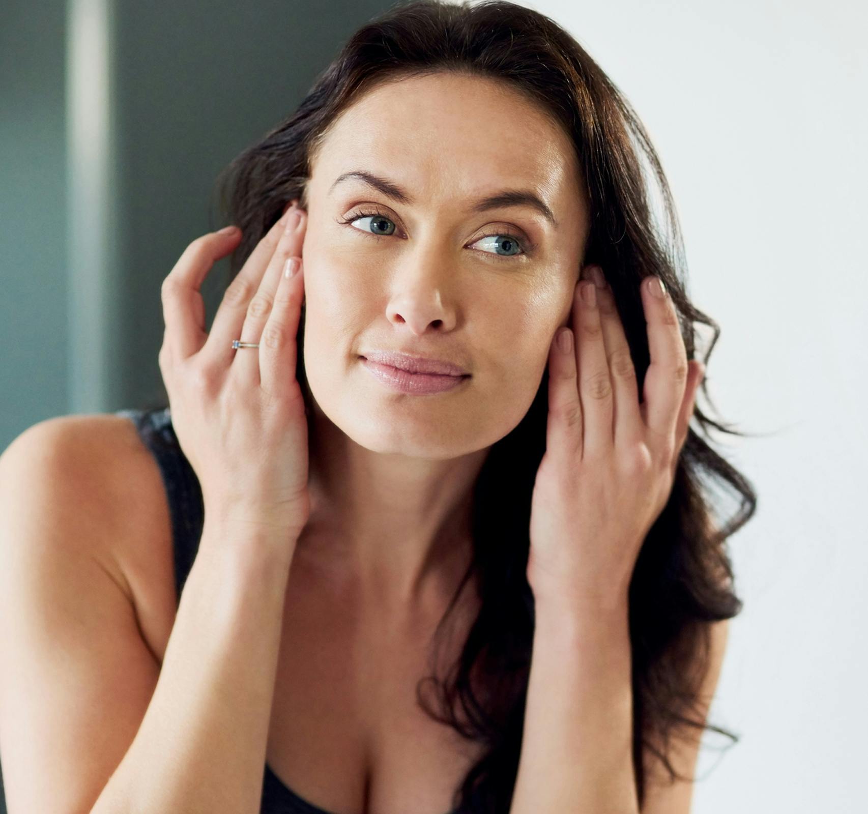 woman pulling hair back to look at face