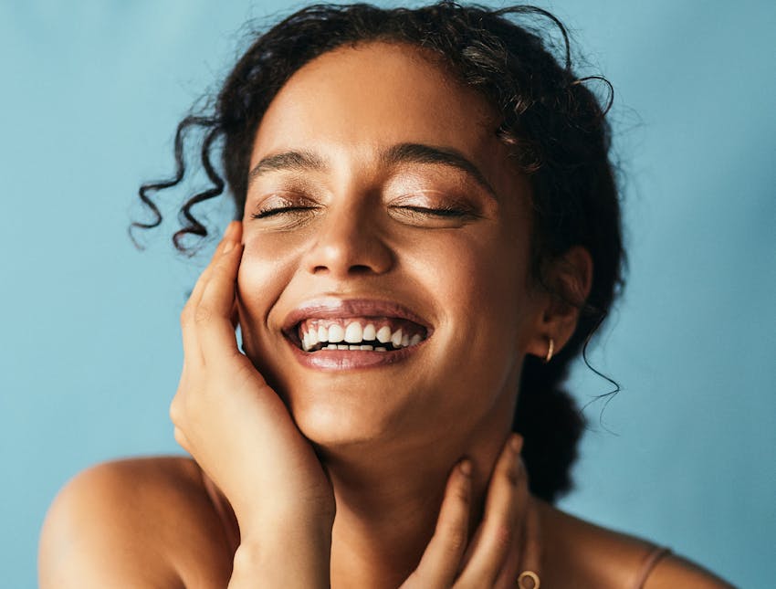 woman smiling and touching her face