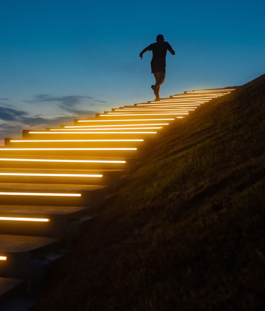 man running up illuminated stairs