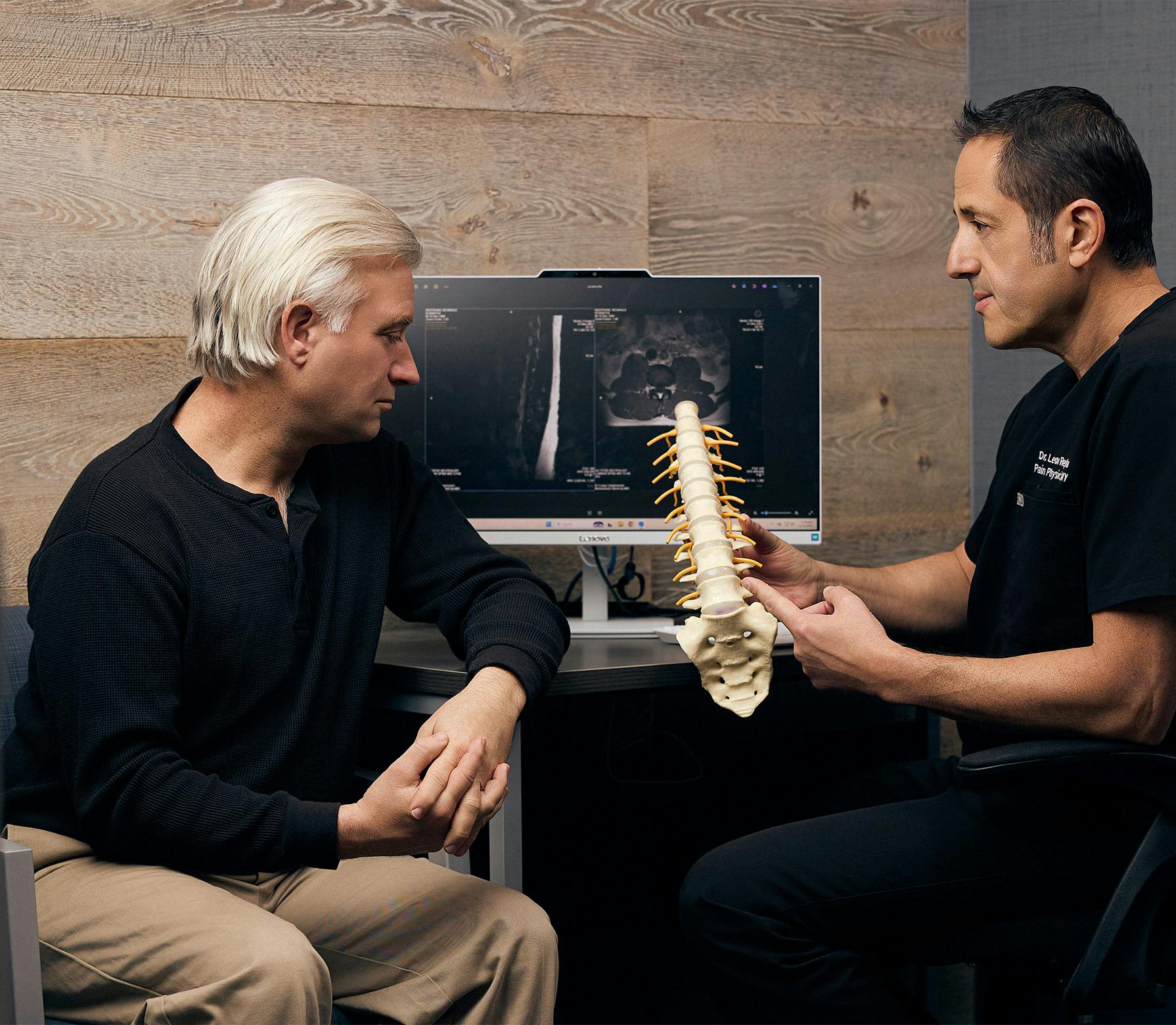 doctor showing a patient a model of a spine