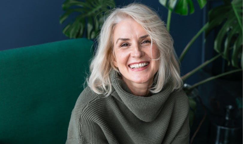 smiling patient in olive turtleneck sitting on green chair