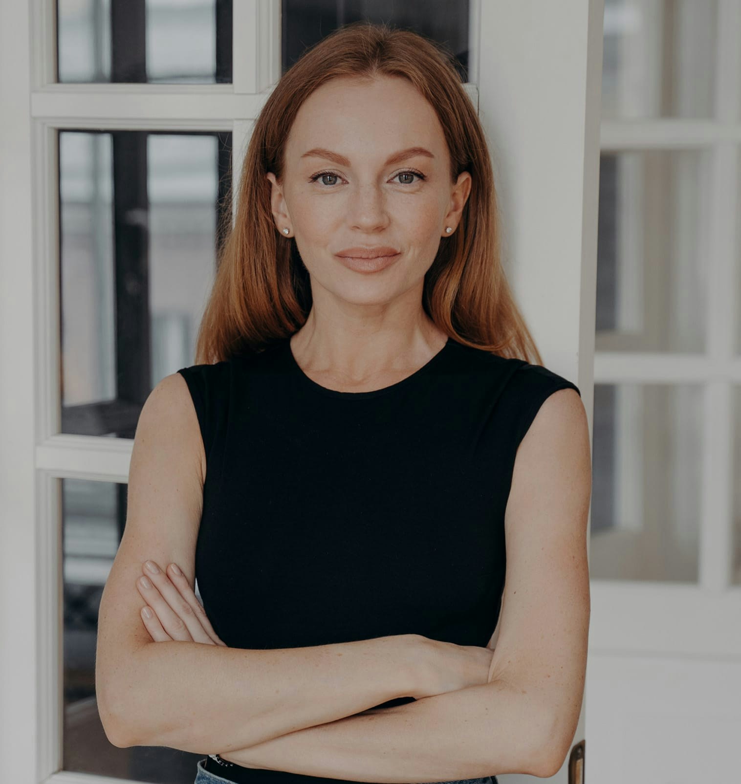 woman wearing black shirt with arms crossed standing in front of french door