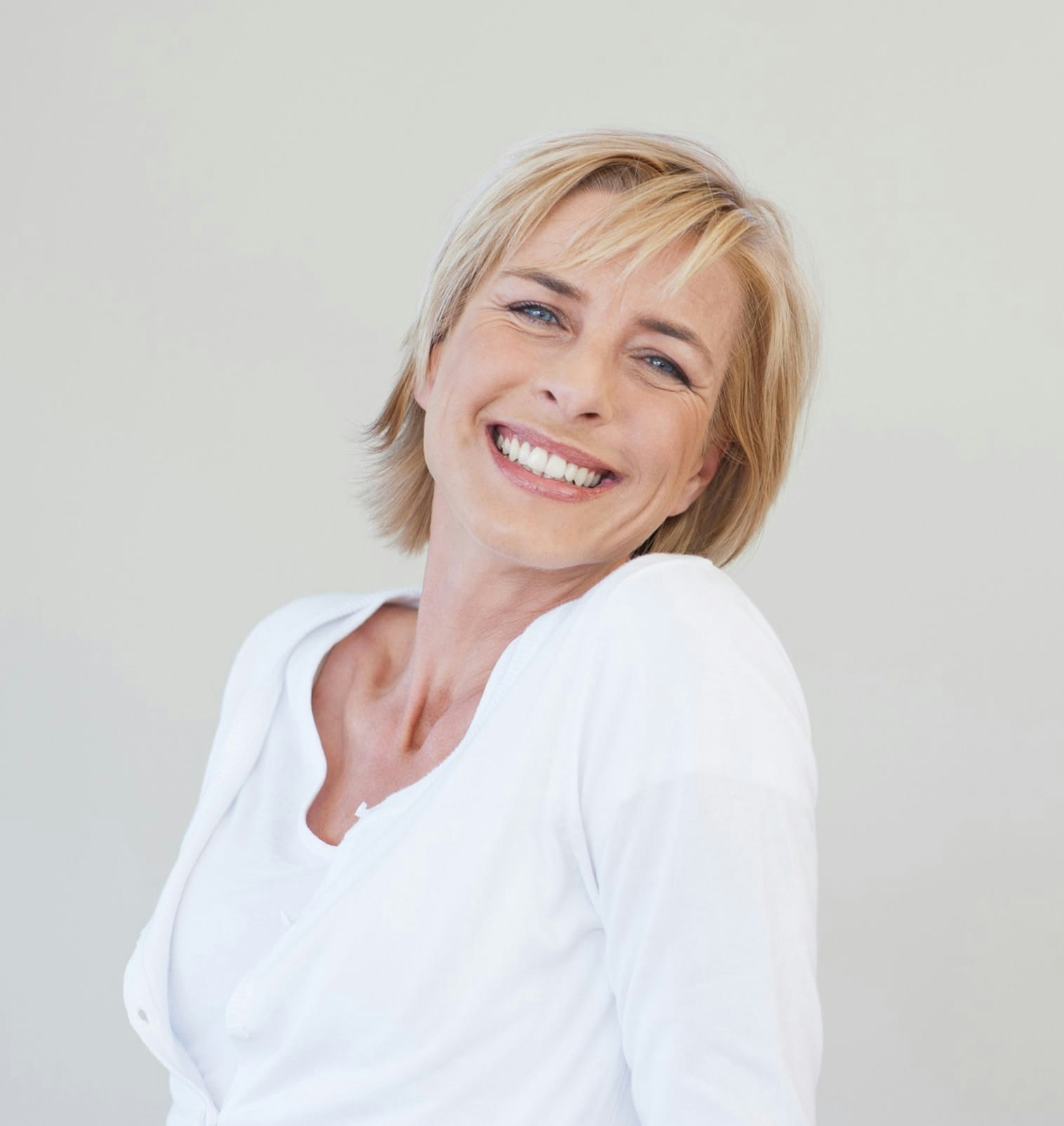 woman smiling in white cardigan with head over left shoulder