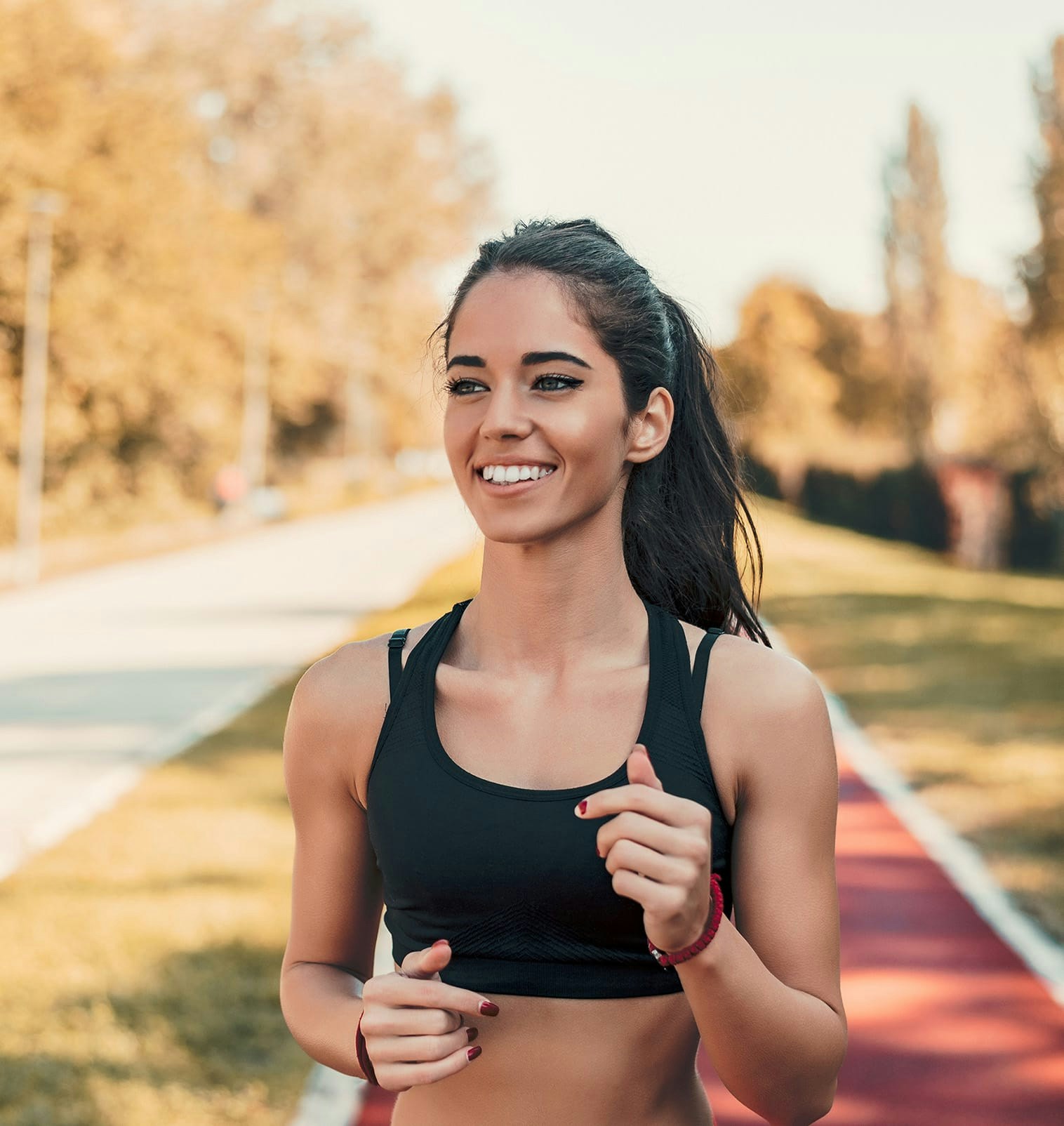 smiling woman in blalck athletic wear jogging on trail