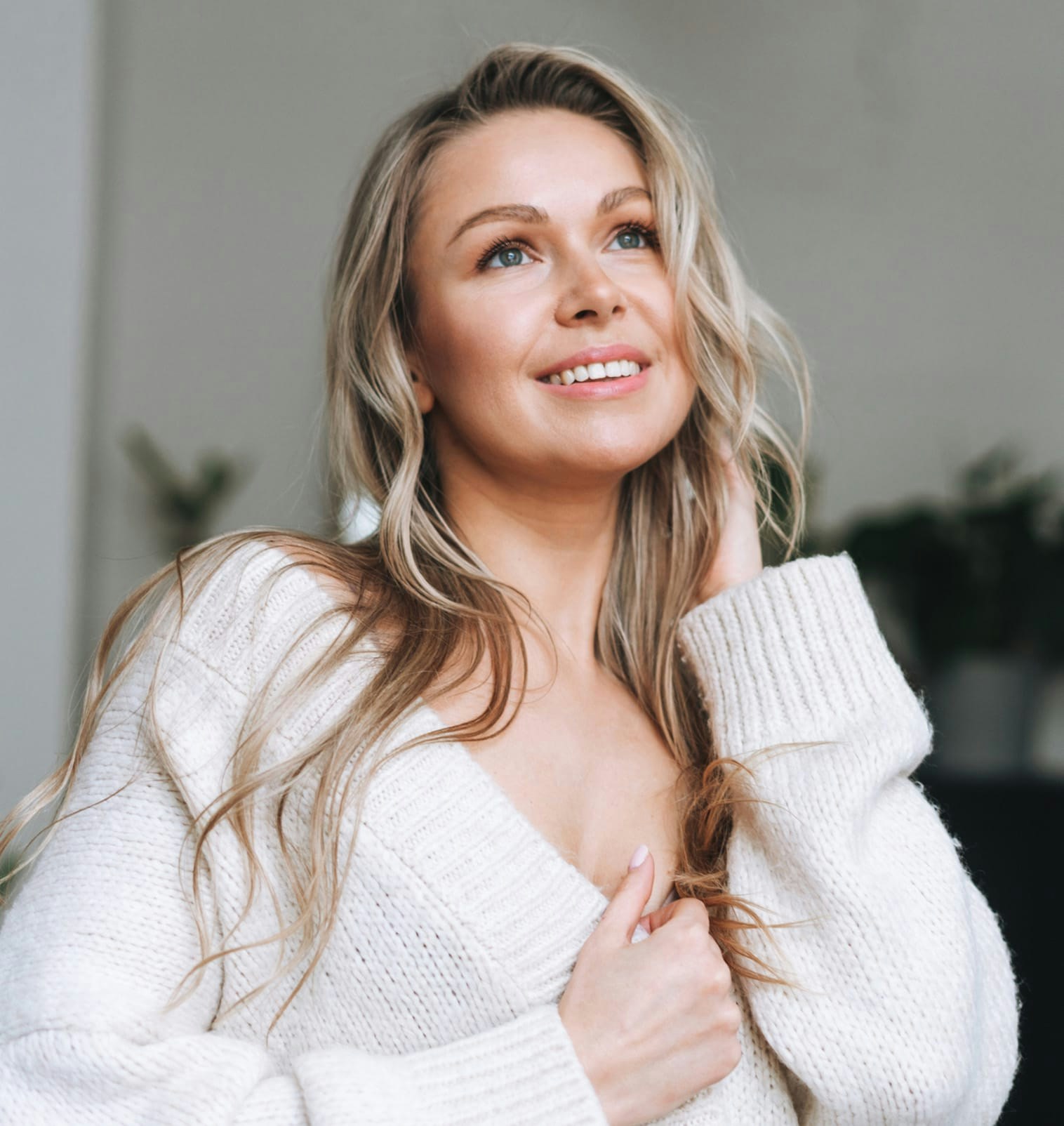 smiling woman wearing knit sweater looking up and to the left
