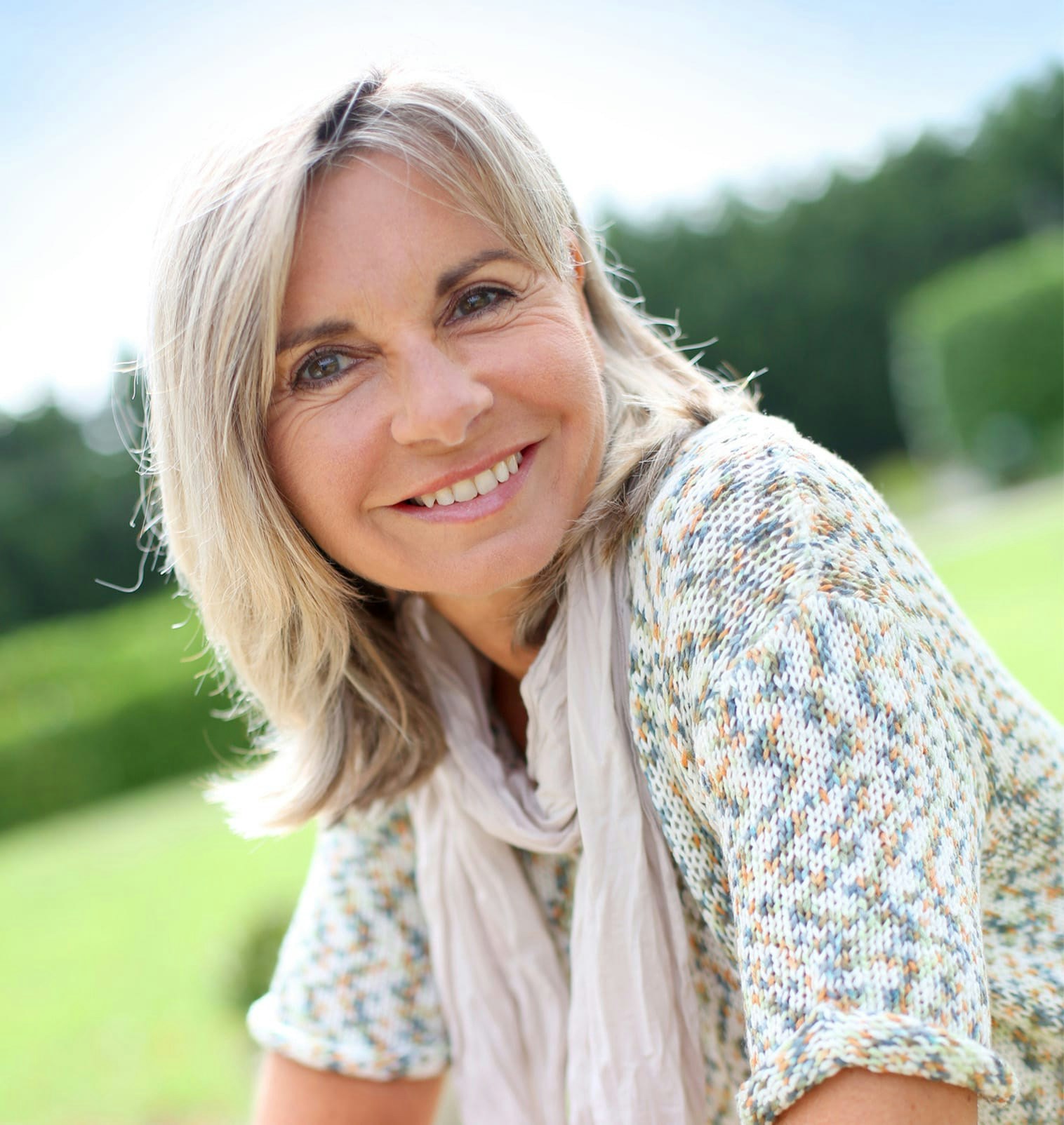 smiling woman outside wearing short sleave sweater and scarf