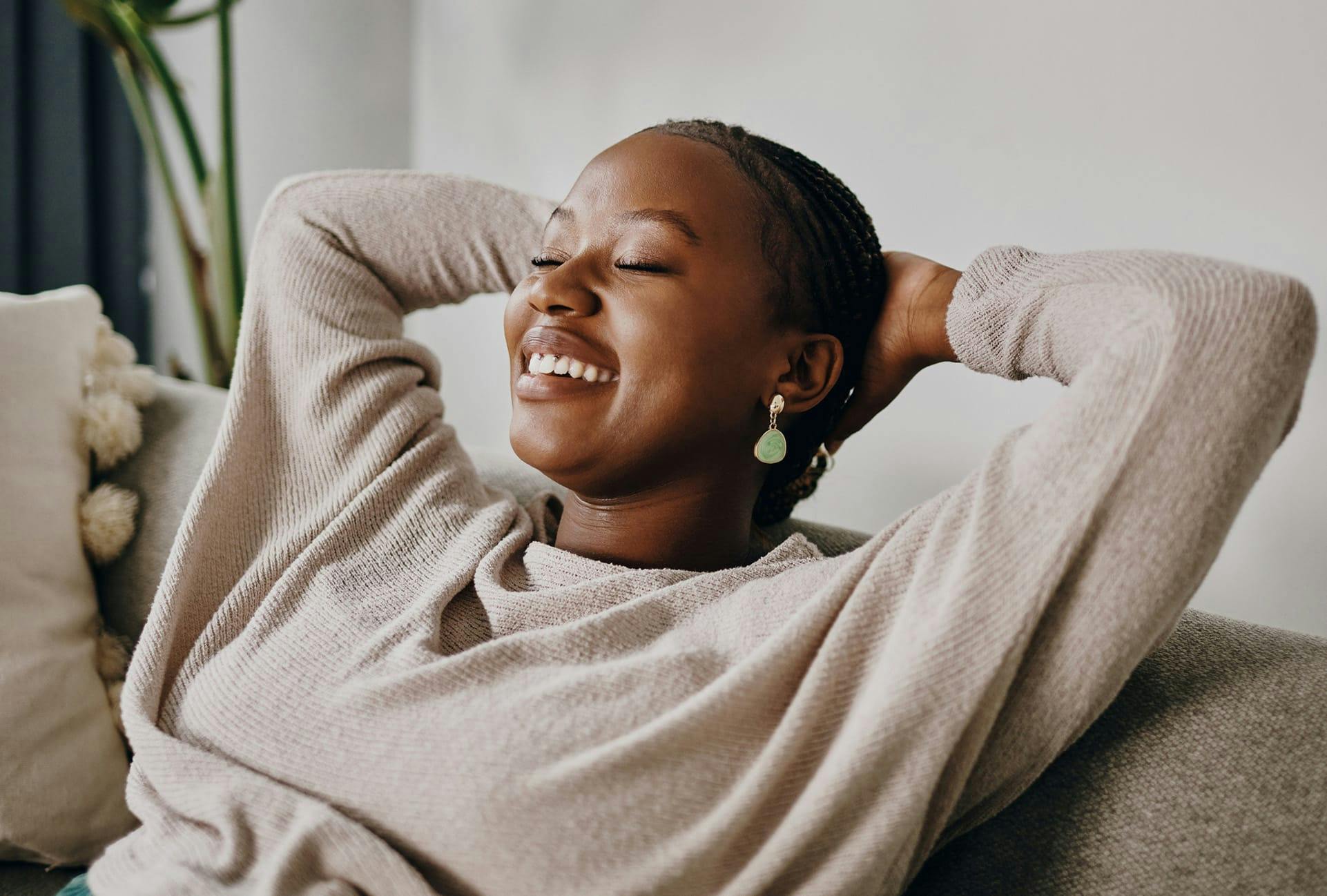 smiling woman leaning back with hands behind head and eyes closed