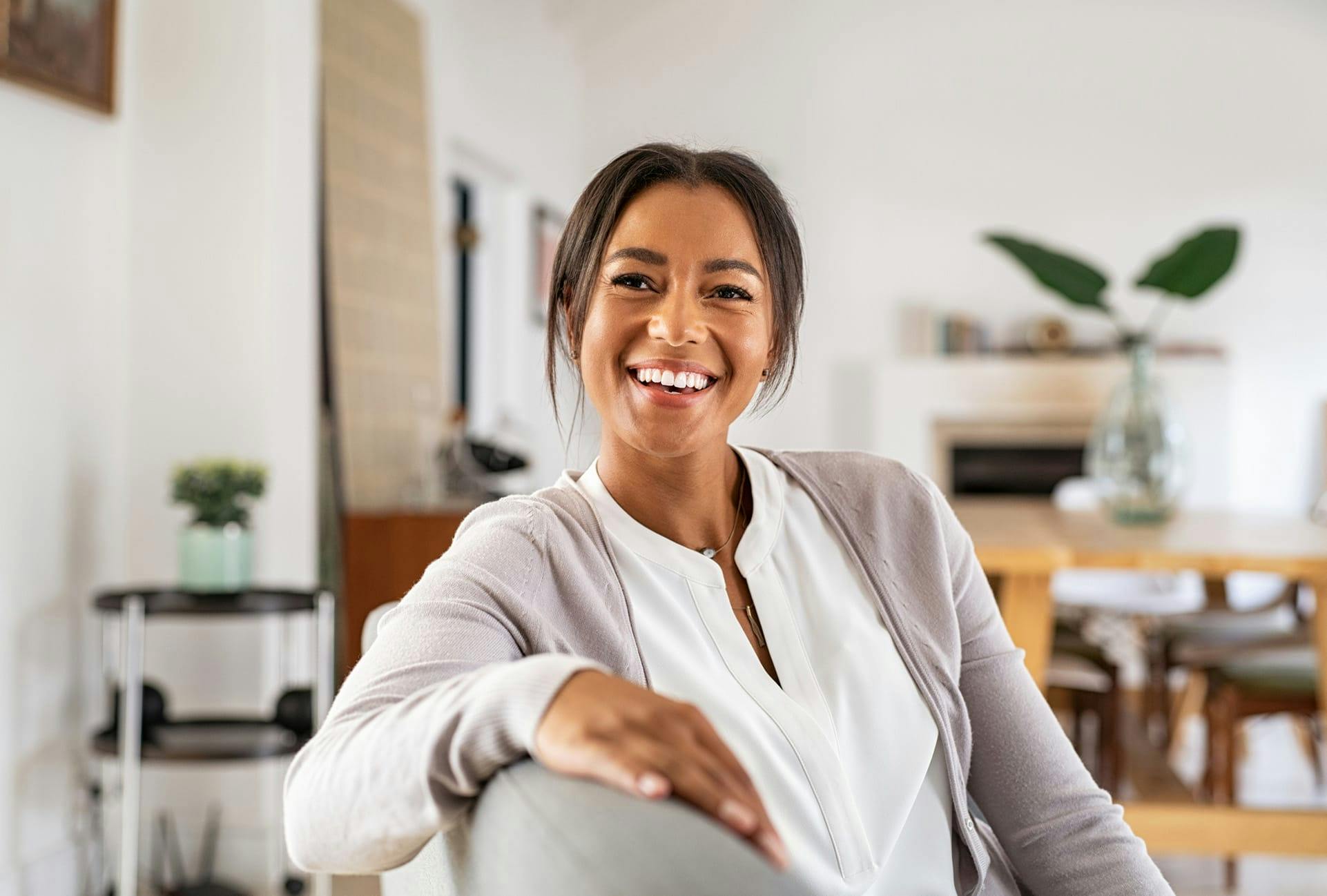 smiling woman in cashmere cardigan sitting with arm on back of chair