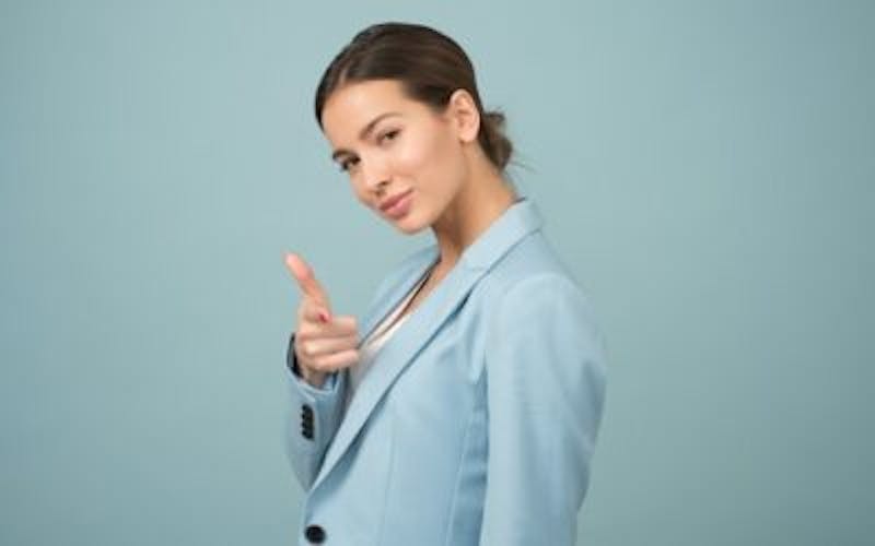 woman in a blue suit pointing at the camera