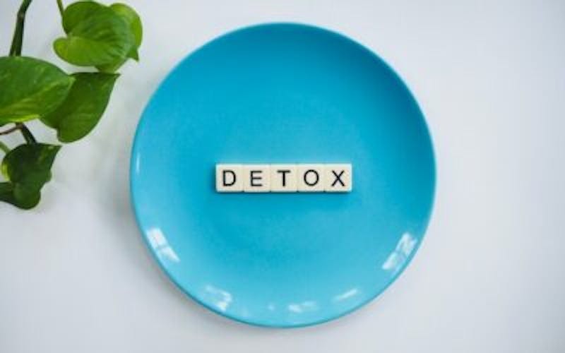 a blue plate with a word detox on it next to a plant