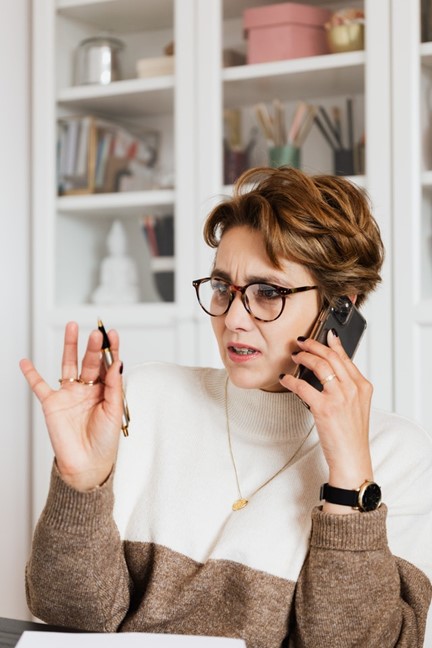 Woman wearing glass on phone holding pen