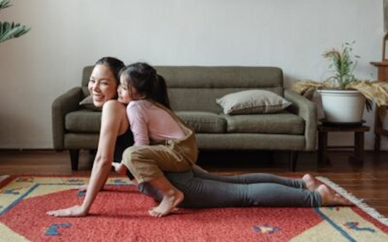 Mom and daughter doing yoga together on the floor