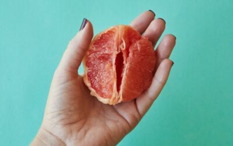 someone holding a grapefruit in their hand on a blue background