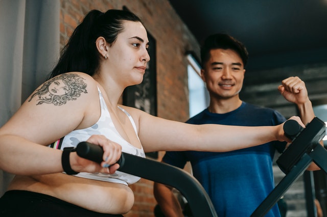 woman on elliptical next to trainer