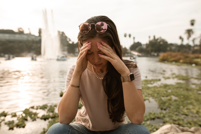 woman sitting near water with face in her hands