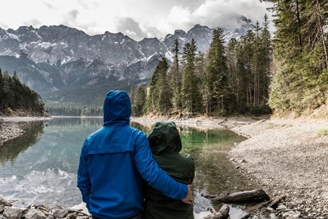 couple stand near lake looking at view