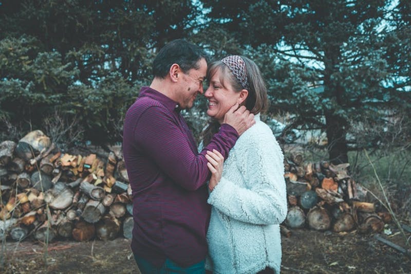 couple standing in front of a pile of wood