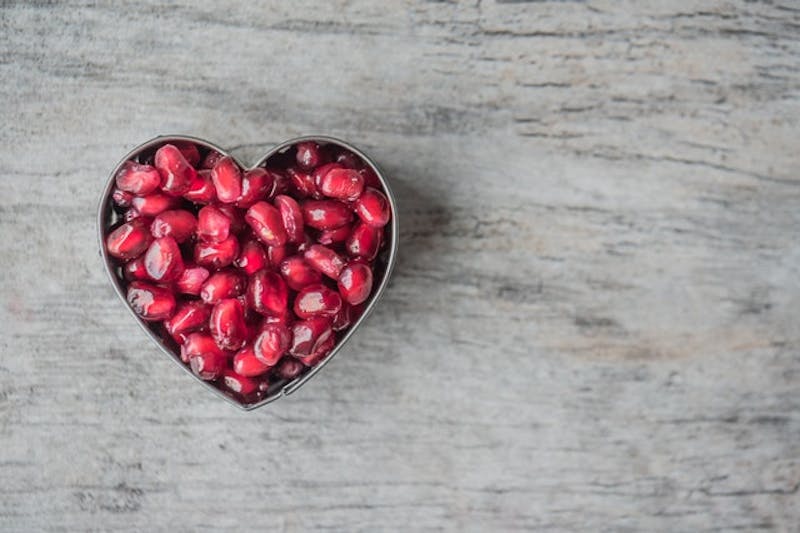 a close up of a heart shaped container filled with pomegranates