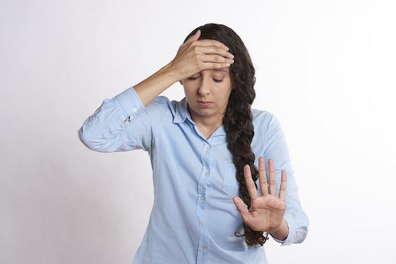 woman with long hair holding her head in pain