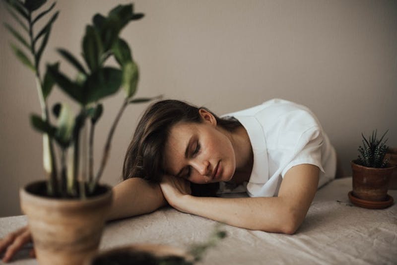 woman sleeping on a table next to a potted plant
