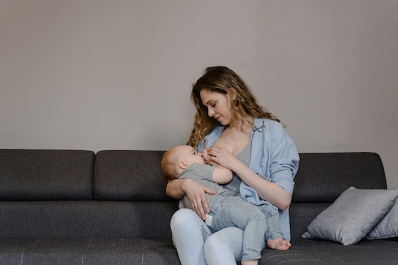 there is a woman holding a baby on a couch