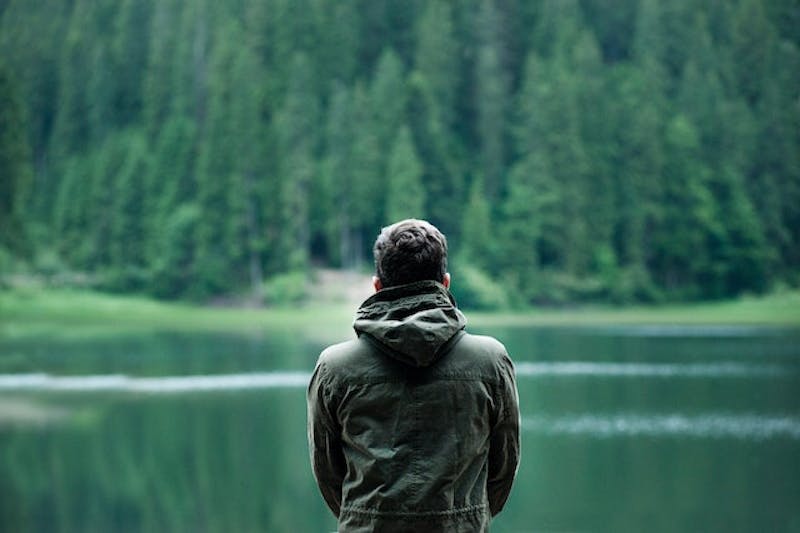 man standing on a dock looking at a lake