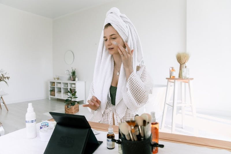 woman in white robe talking on tablet while sitting at desk