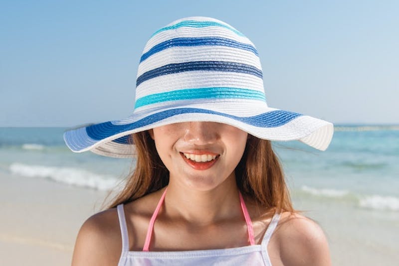 woman in a white and blue hat on the beach