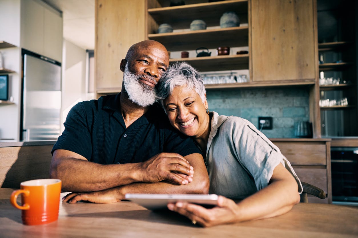 couple sitting together and laughing at tablet