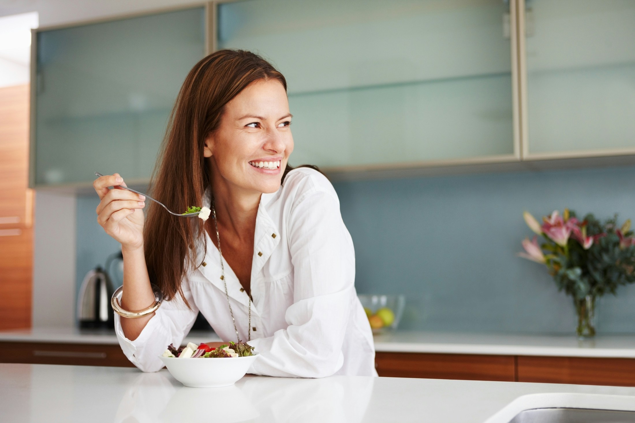 woman smiling while eating a salad