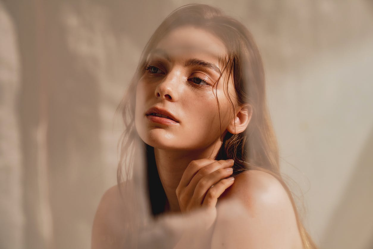 Woman with perfect skin stairs off camera with a flowing sheet behind her. Her youthful skin emulates the potential results Fractional Laser Skin Resurfacing in Thousand Oaks