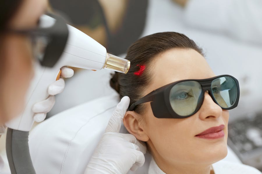 Woman wearing light protective glasses in order to receive the Fotona hair restoration treatement with the er: YAG laser