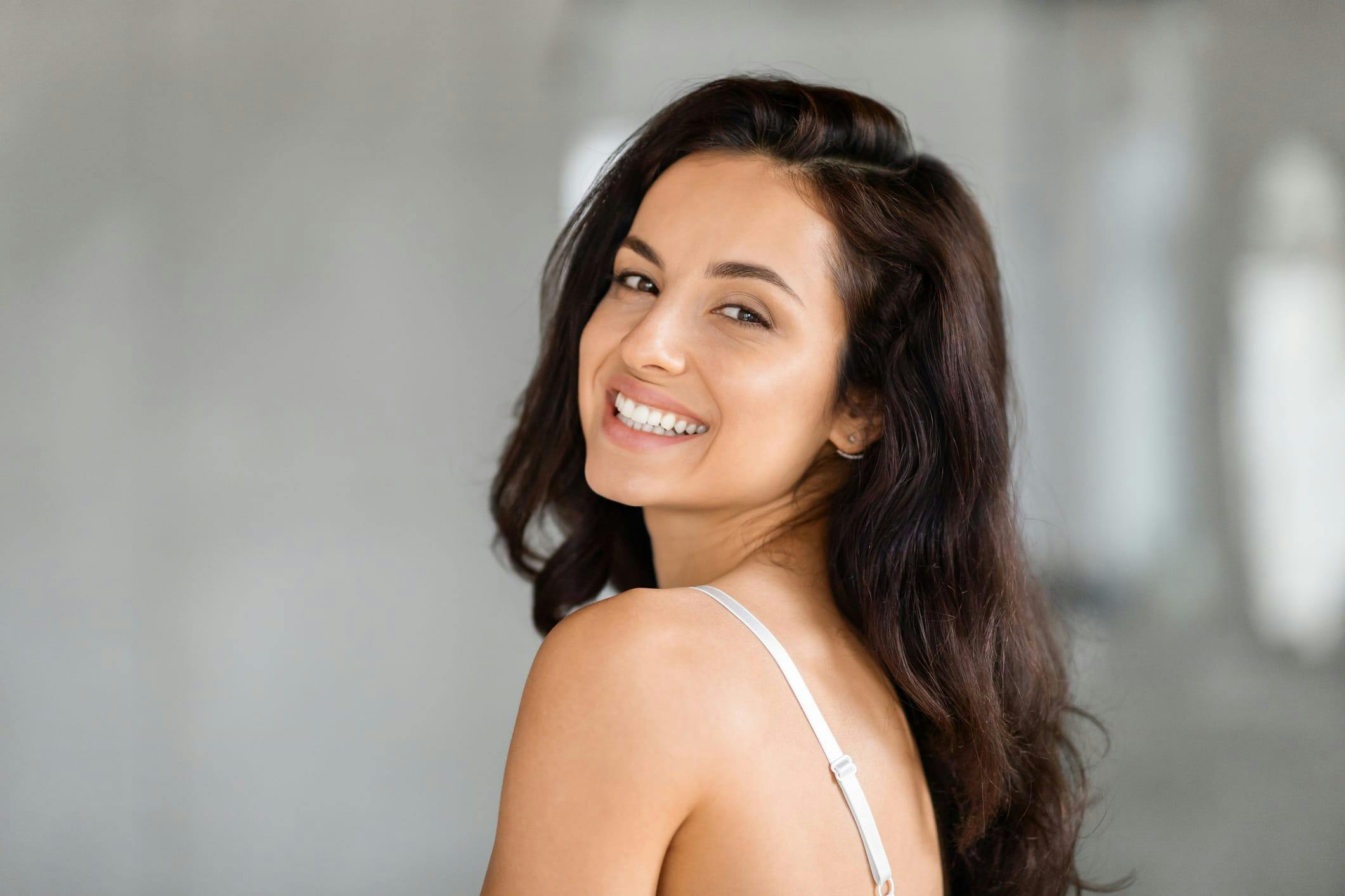 Dark-haired woman smilin gover her shoulder