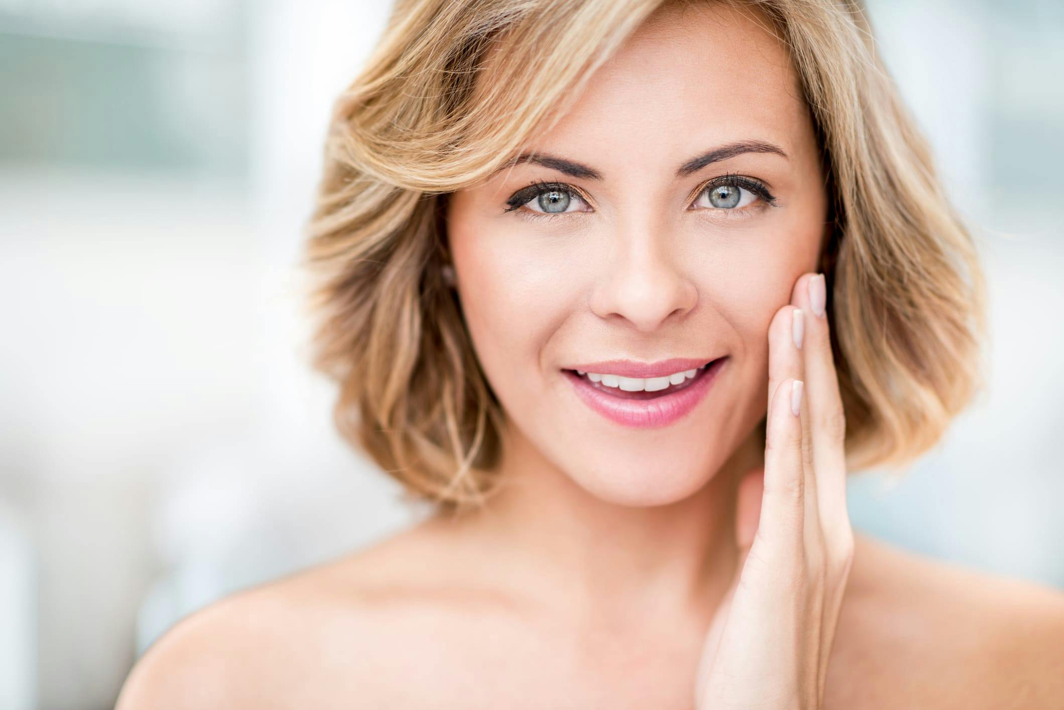 Woman with short hair running her hand over her cheek