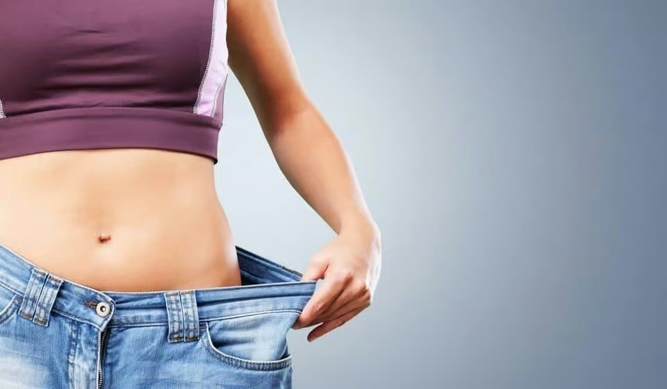Woman tugging pants waistband to show weight loss