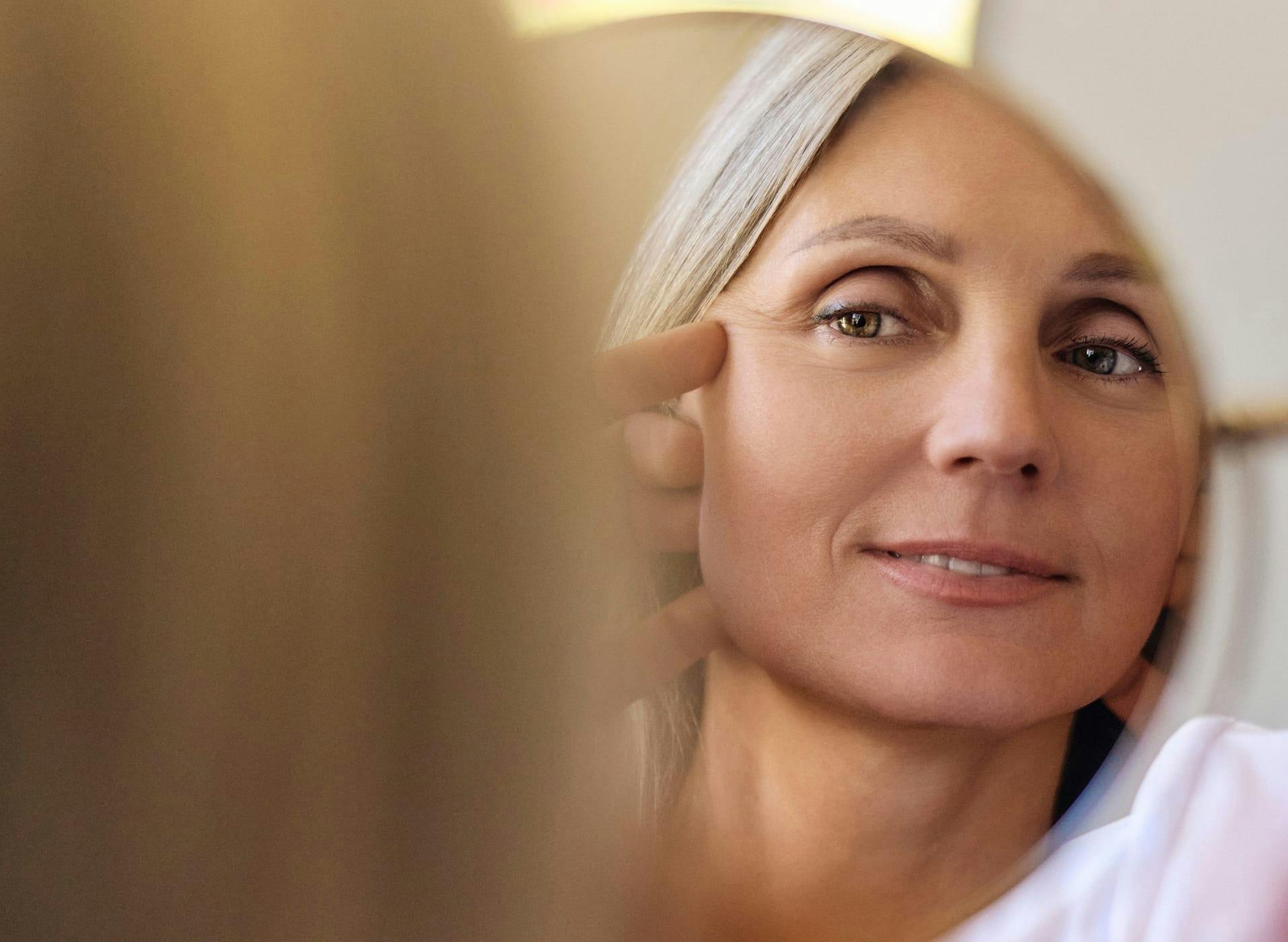 woman looking at her reflection in a mirror