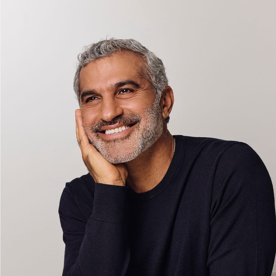 Dr. Karam smiling and touching his face