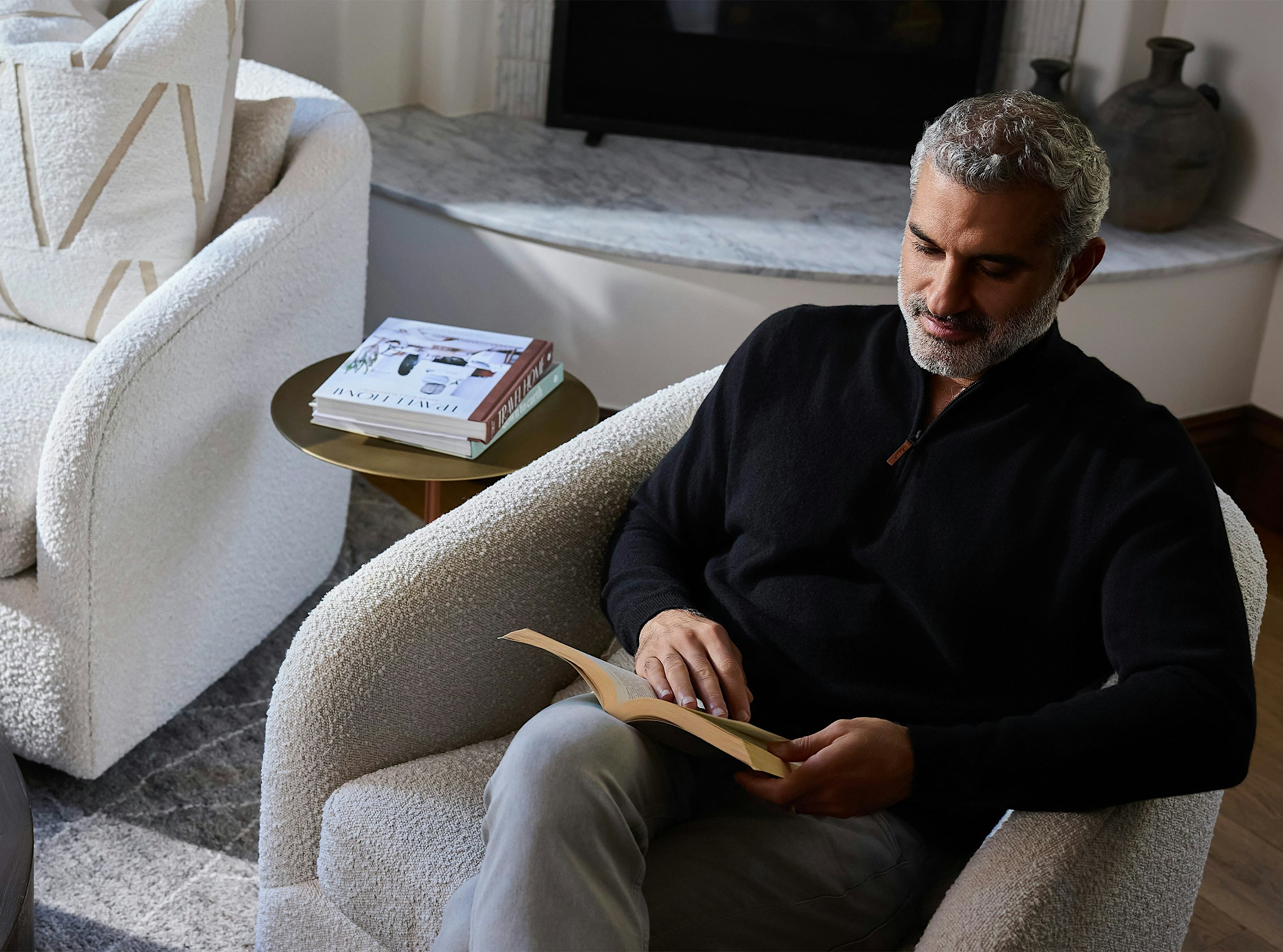 Dr. Karam sitting in a chair and reading a book