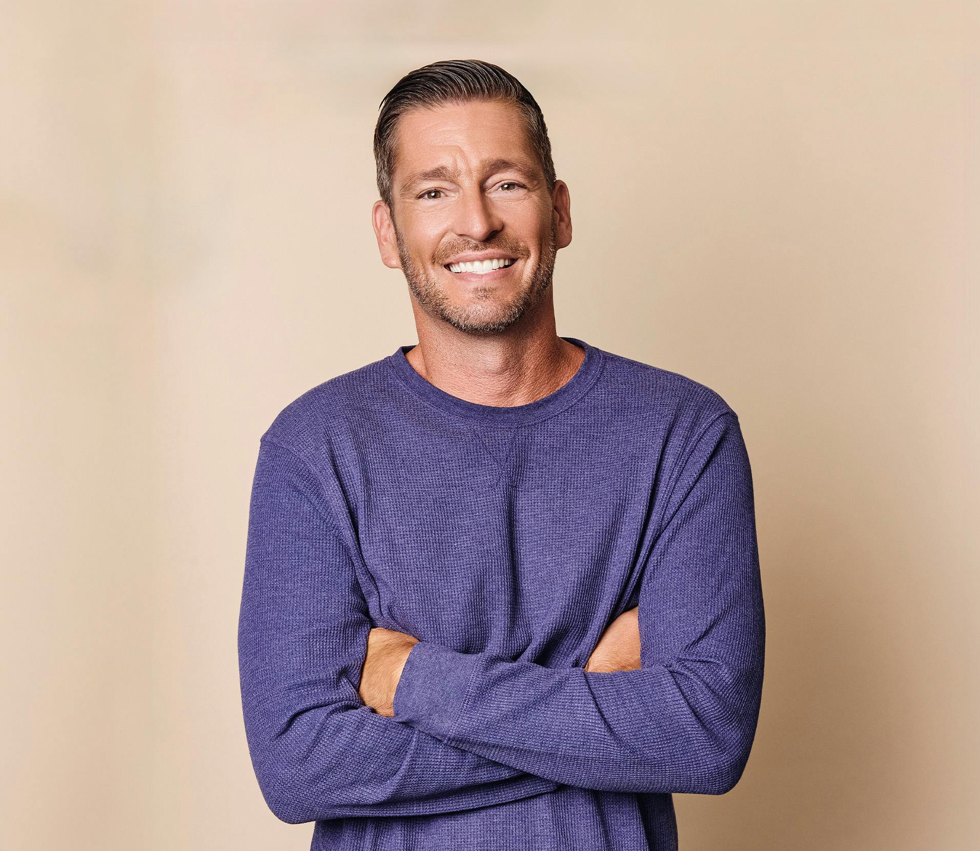 A man smiling with his arms crossed