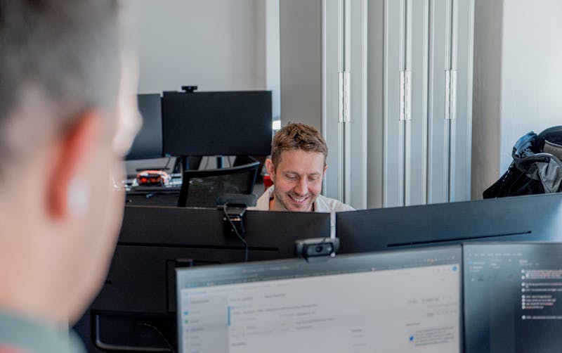 A man smiling while working at a computer in an office for a ServiceNow partner.