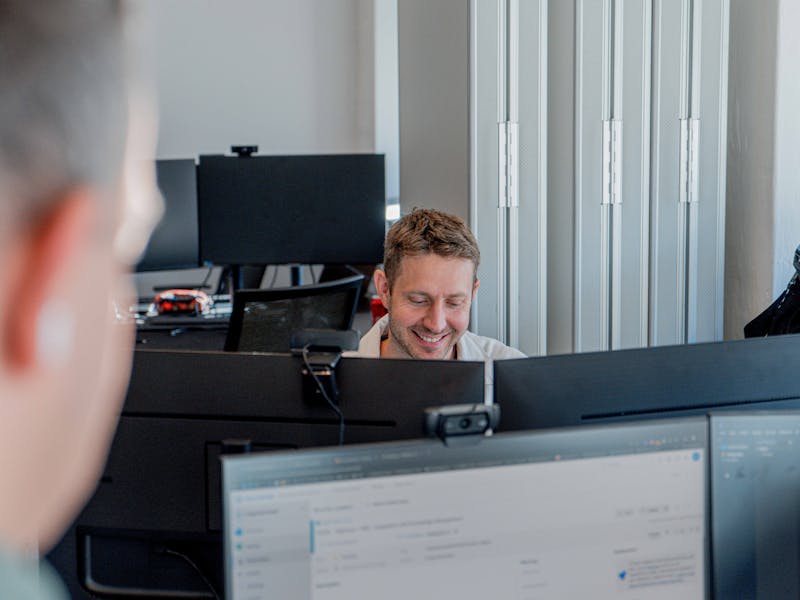 A man smiling while working at a computer in an office for a ServiceNow partner.