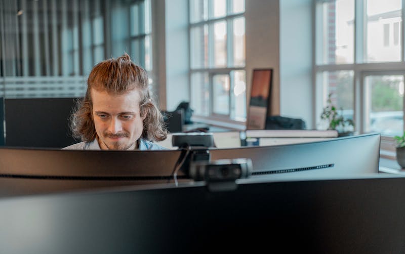 A man working at a computer in an office at ServiceNow partner Adeno.