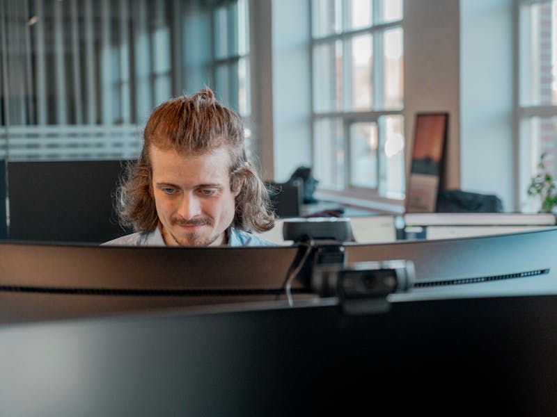 A man working at a computer in an office at ServiceNow partner Adeno.