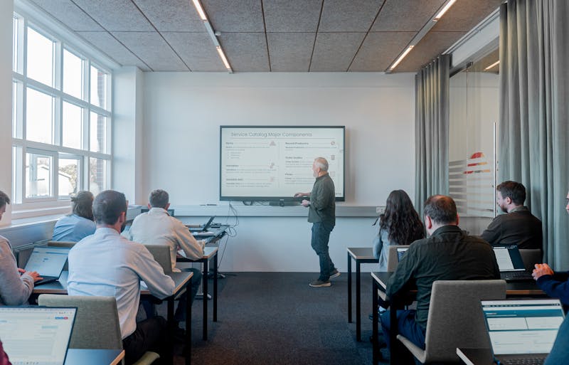 A man presenting a slide titled Service Catalog Major Components about ServiceNow to a group in a classroom.