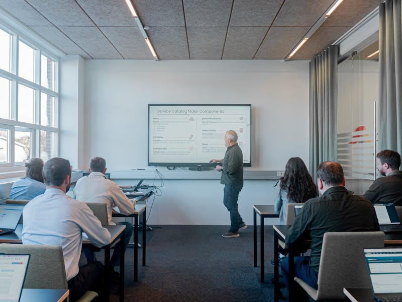 A man presenting a slide titled Service Catalog Major Components about ServiceNow to a group in a classroom.