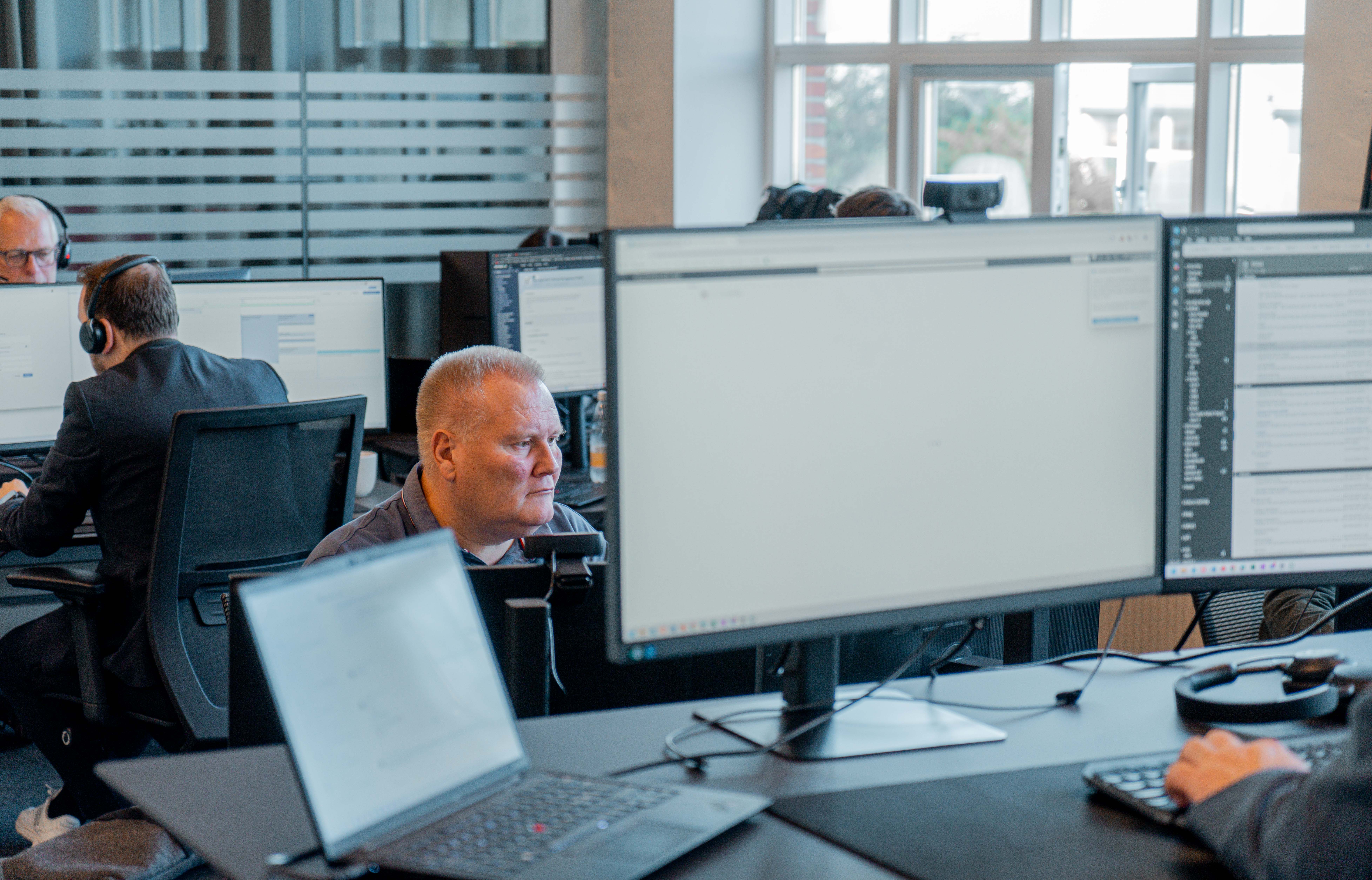 Professionals working at computer workstations in a modern office environment using ServiceNow.