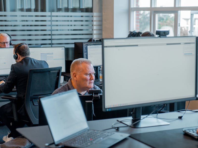 Professionals working at computer workstations in a modern office environment using ServiceNow.