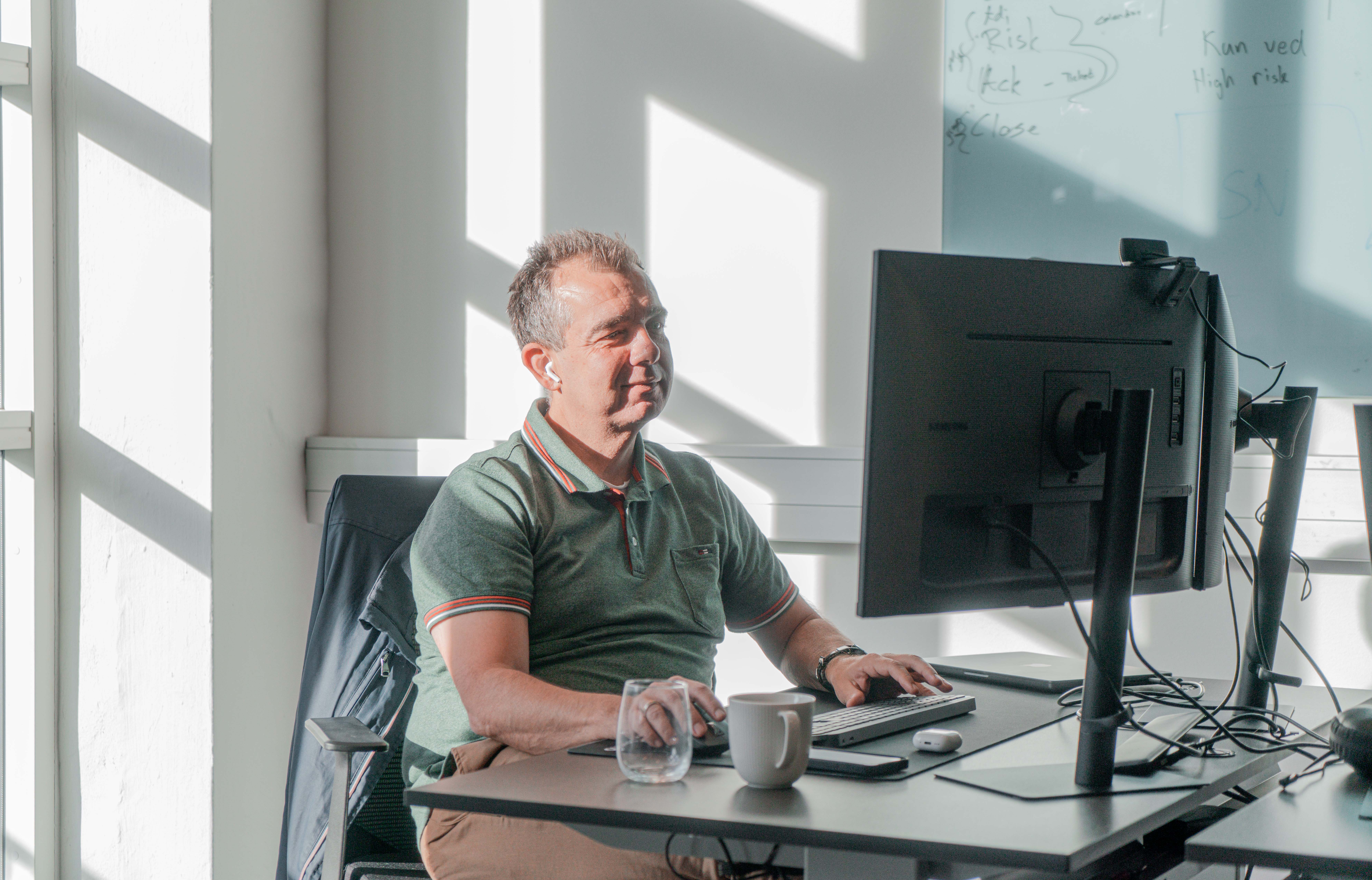 A man working at a computer desk in a bright office at a ServiceNow partner.