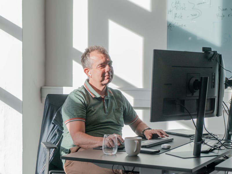 A man working at a computer desk in a bright office at a ServiceNow partner.
